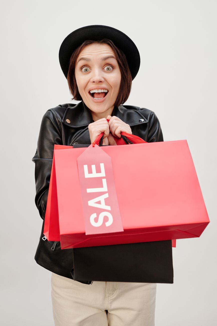 Excited woman holding red sale shopping bags
